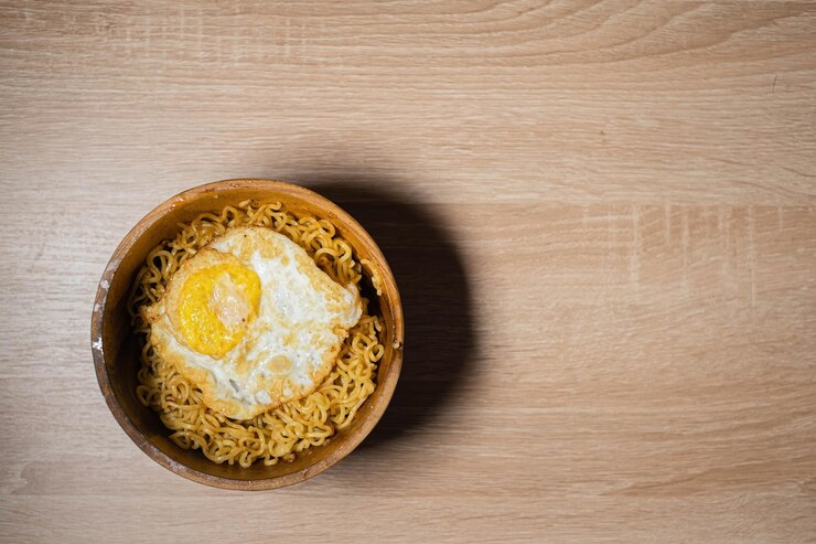 Fideos fritos y huevo SunnySide Up en un tazón de madera