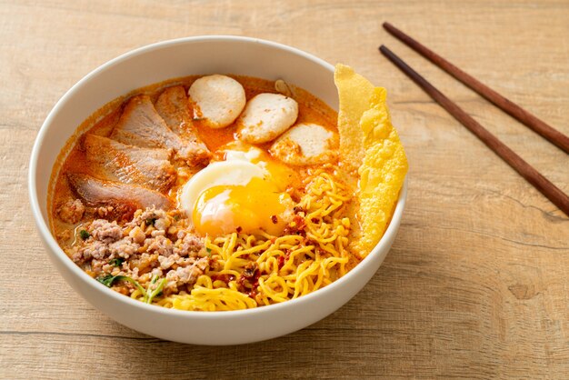 fideos de huevo con carne de cerdo y albóndigas en sopa picante o Tom Yum Noodles al estilo asiático