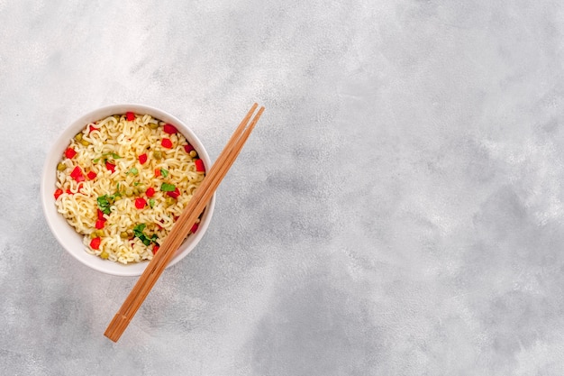 Fideos de huevo instantáneos asiáticos tradicionales en un plato con palillos