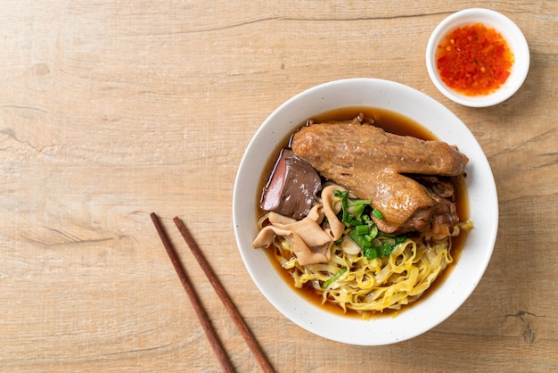 Fideos de huevo con pato guisado y estofado en sopa marrón