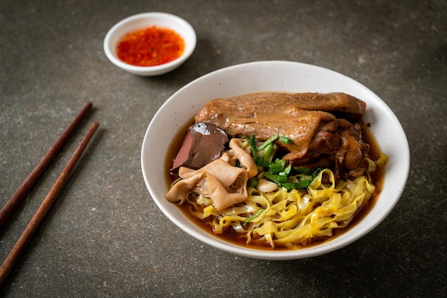 Fideos de huevo con pato guisado y estofado en sopa marrón