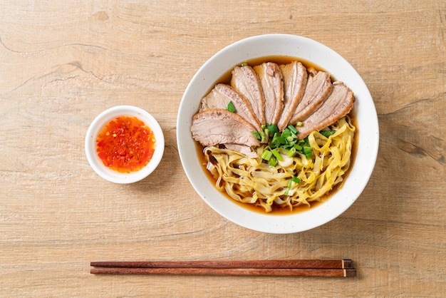 Fideos de huevo con pato guisado en sopa marrón