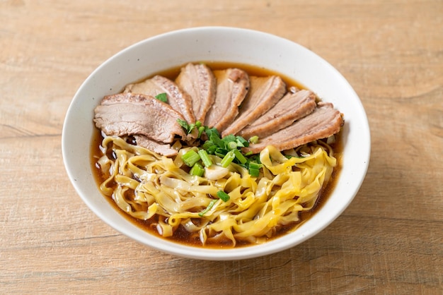 Fideos de huevo con pato guisado en sopa marrón