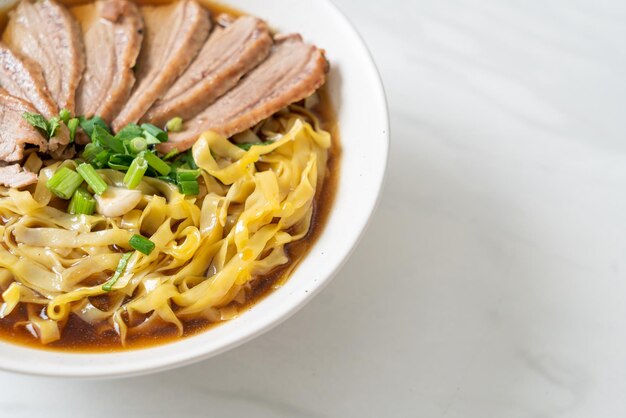 Fideos de huevo con pato guisado en sopa marrón