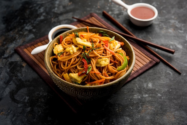 Fideos de huevo Schezwanor hakka, comida popular indochina servida en un cuenco con palillos. enfoque selectivo