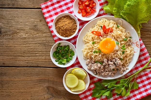 Fideos instantáneos cocinando sabroso comer con tazón sopa de fideos tazón de fideos con huevo cocido cerdo picado verduras cebolleta limón lima lechuga apio y chile en la comida de la mesa