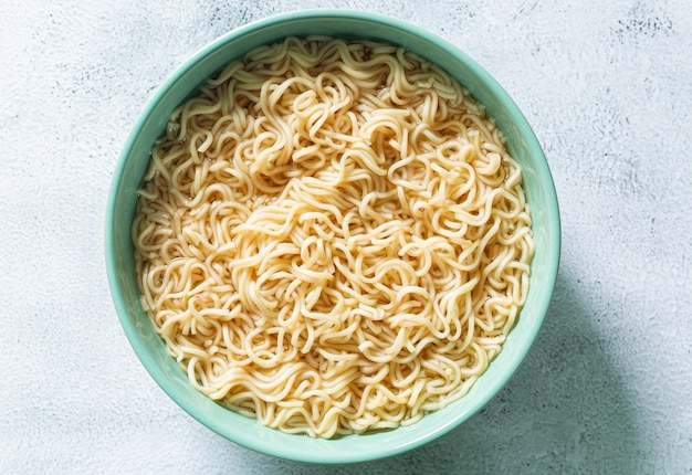 Fideos instantáneos Concepto de comida sabrosa con plato de fideos sobre fondo gris