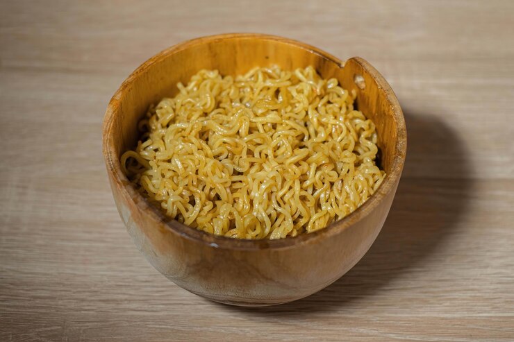 Fideos instantáneos fritos en un tazón de madera y una mesa de madera