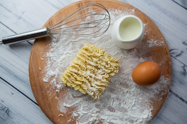 fideos instantáneos huevos leche y un batidor vista desde arriba Enfoque selectivo