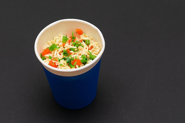 Fideos instantáneos preparados con zanahoria y verduras en taza azul