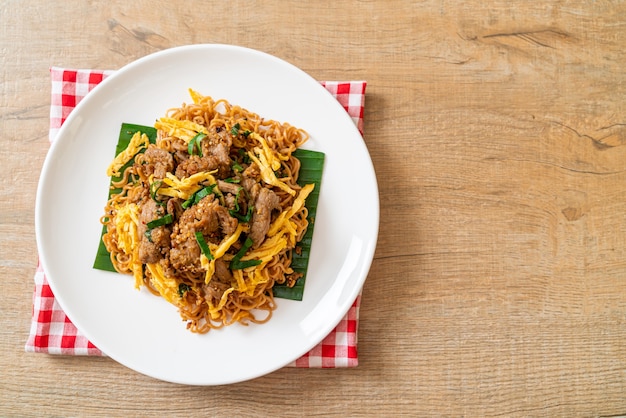 fideos instantáneos salteados con cerdo y huevo - estilo de comida callejera local asiática