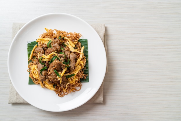 fideos instantáneos salteados con cerdo y huevo - estilo de comida callejera local asiática