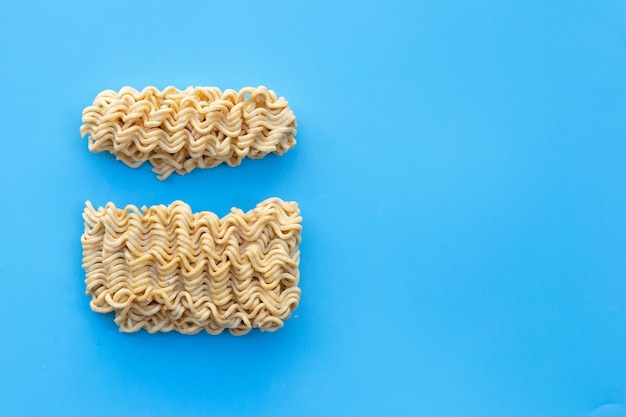 Fideos instantáneos secos sobre fondo azul.