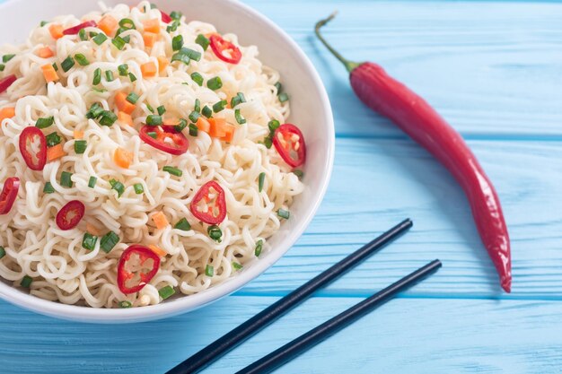 Fideos instantáneos en un tazón con chiles, cebolla y zanahorias