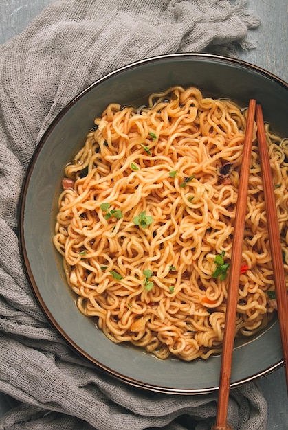 Fideos instantáneos en un tazón sobre una mesa gris vista superior sin gente