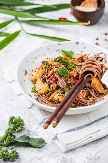 Fideos japoneses de alforfón Yakisoba con pollo y verduras sobre un fondo claro