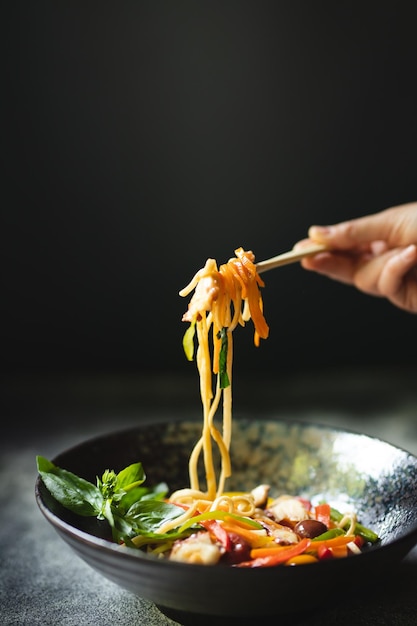 Fideos con mariscos y verduras sobre un fondo oscuro. Comida asiática.