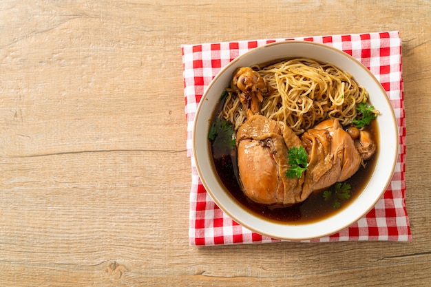 Fideos con pollo estofado en un tazón de sopa marrón - estilo de comida asiática