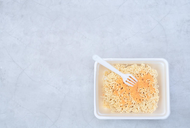 Fideos rizados chinos instantáneos sin cocer en envases para llevar con tenedor de plástico Enfoque selectivo Comida asiática y concepto de entrega Alimentación no saludable