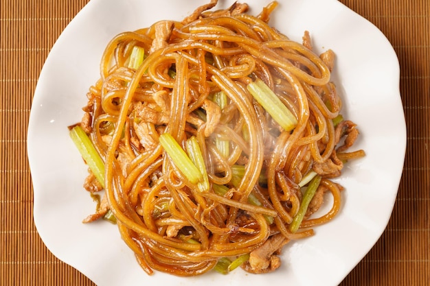 Fideos salteados con apio, una comida china característica en un fondo monocromático