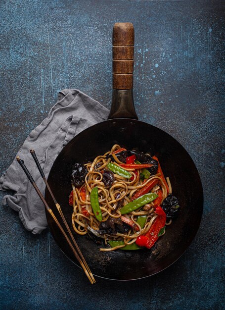 Fideos salteados asiáticos con verduras en una sartén wok negra