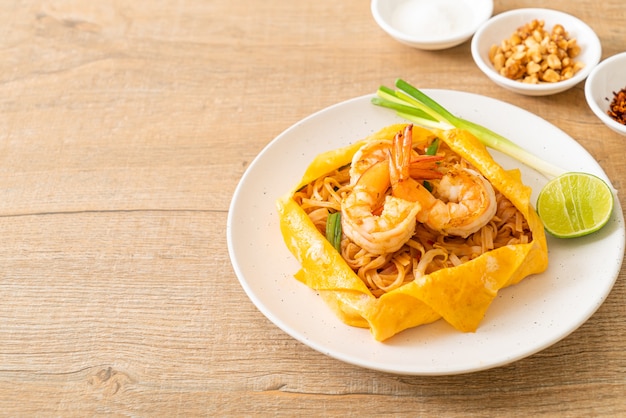 Fideos salteados tailandeses con camarones y envoltura de huevo (Pad Thai) - Estilo de comida tailandesa