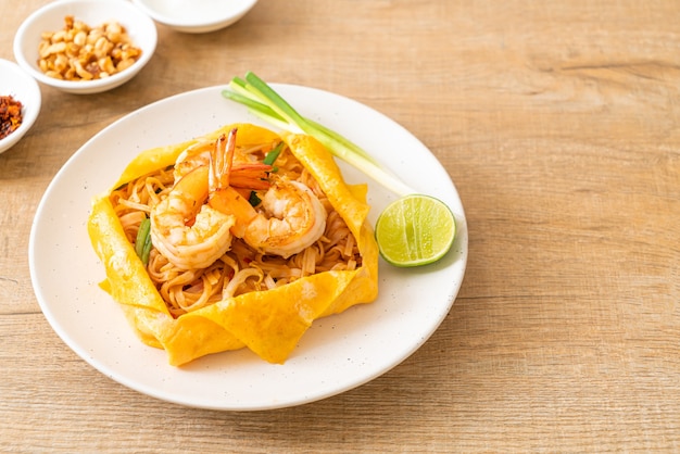 Fideos salteados tailandeses con camarones y envoltura de huevo (Pad Thai) - Estilo de comida tailandesa