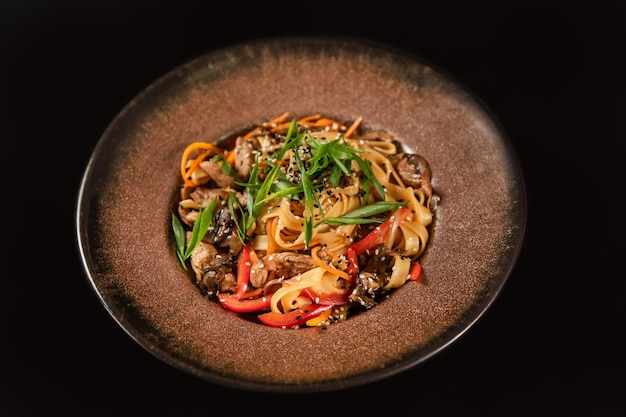 Fideos salteados con verduras y camarones en un tazón negro Fondo de pizarra Vista superior Espacio de copia