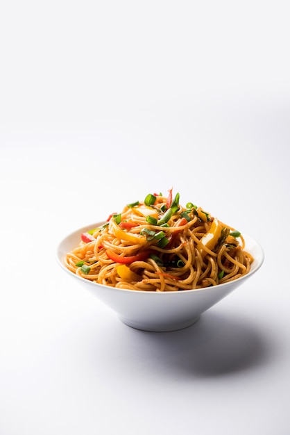 Los fideos Schezwan o los fideos Hakka de verduras o chow mein son recetas populares indochinas, que se sirven en un tazón o plato con palillos de madera.