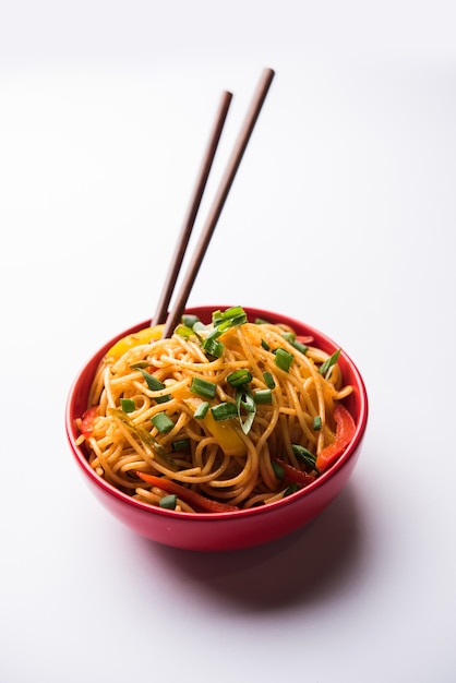 Los fideos Schezwan o los fideos Hakka de verduras o chow mein son recetas populares indochinas, que se sirven en un tazón o plato con palillos de madera.