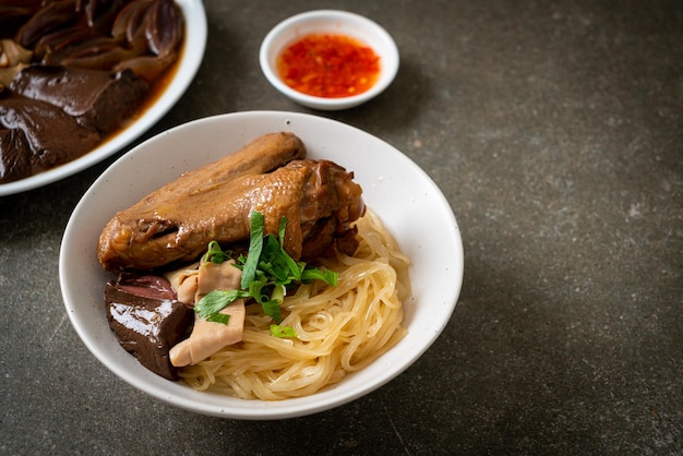 Fideos secos con pato estofado en tazón blanco