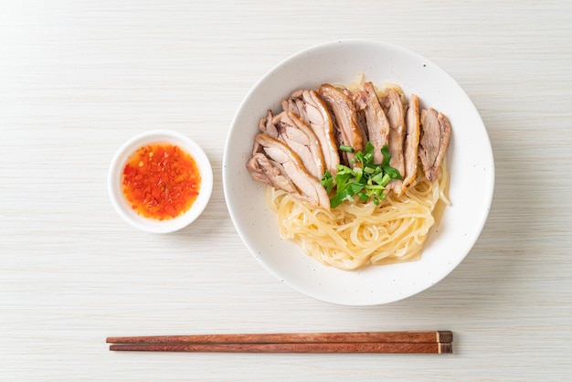 Fideos secos con pato guisado en tazón blanco