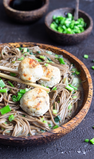 Fideos Soba servidos con albóndigas de pollo y cebolla verde.