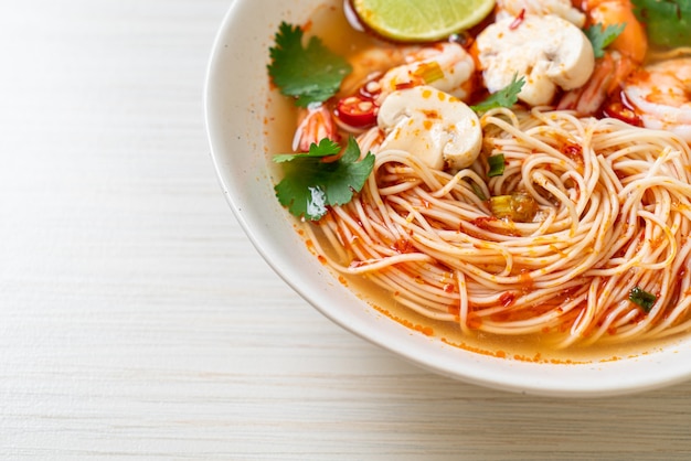 fideos con sopa picante y camarones en un tazón blanco (Tom Yum Kung) - estilo de comida asiática