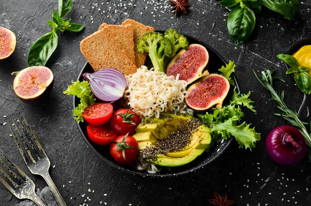 Fideos de tazón de Buda de comida con higos de aguacate chia y lechuga en un plato de piedra negra Vista superior Espacio libre para el texto