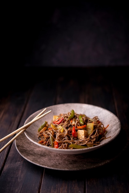 Foto fideos en un tazón con palillos y espacio de copia