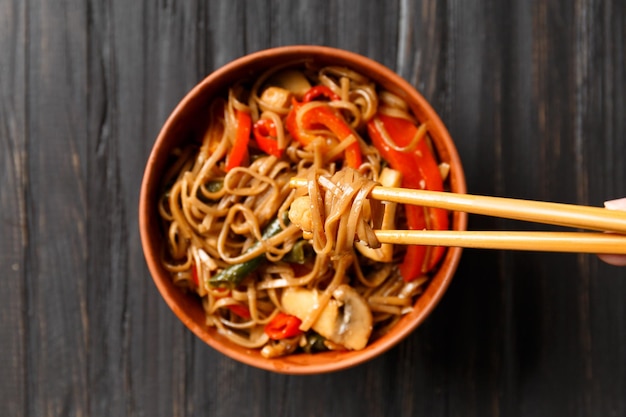 Fideos de trigo sarraceno con verduras y carne de pollo sobre un fondo oscuro