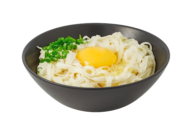 Fideos udon con huevo crudo y hierbas en un recipiente gris aislado sobre fondo blanco con trazado de recorte