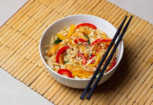 Fideos udon con pollo, pimiento y sésamo. Comida china.