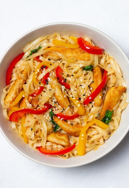 Fideos udon con pollo, pimiento y sésamo. Comida china.