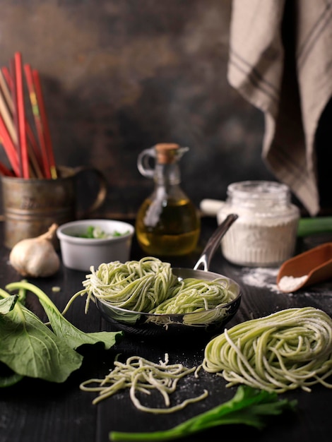 Fideos de vegetales verdes asiáticos crudos caseros en el proceso de cocción casera en la cocina Mie Sawi Sayur