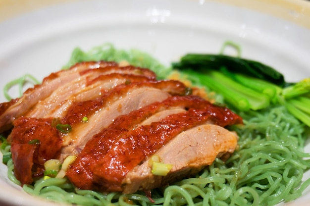 Foto fideos verdes chinos con pato asado y vegetales.