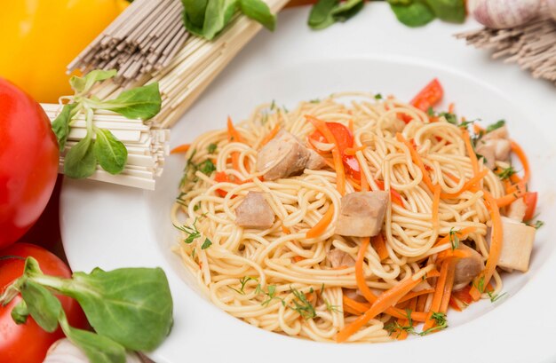 Fideos con verduras y guarnición en plato blanco