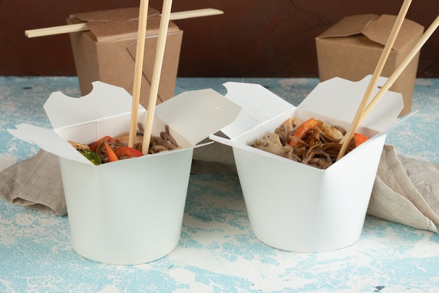 Foto fideos con verduras y pollo en envases artesanales