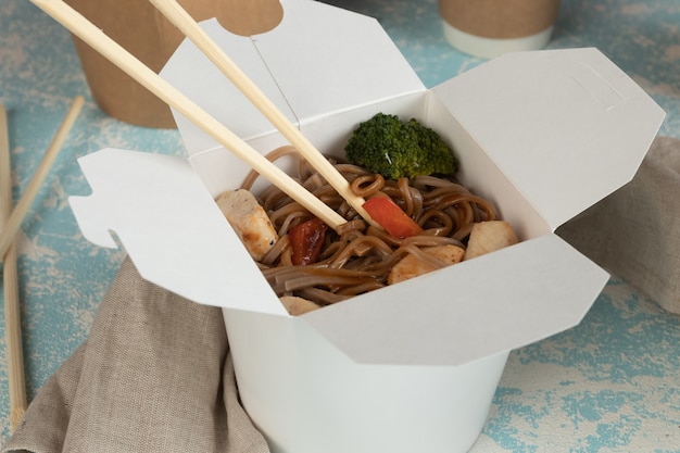 Foto fideos con verduras y pollo en envases artesanales