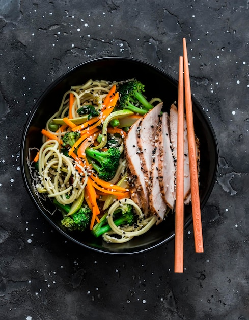 Fideos con verduras salteadas y rodajas finas de pastrami de pollo en una vista superior de fondo oscuro Delicioso almuerzo de estilo asiático