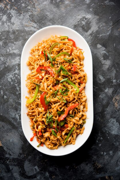 Los fideos de verduras Schezwan son unos fideos Hakka planos salteados picantes y sabrosos con salsa y verduras. servido con palillos. enfoque selectivo