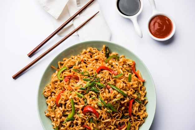 Los fideos de verduras Schezwan son unos fideos Hakka planos salteados picantes y sabrosos con salsa y verduras. servido con palillos. enfoque selectivo