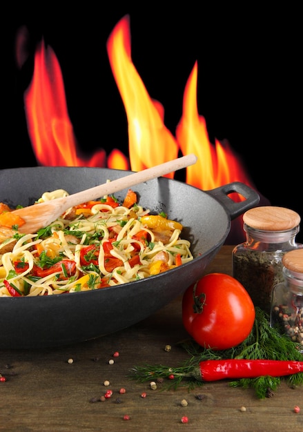Fideos con verduras en wok sobre fondo de fuego