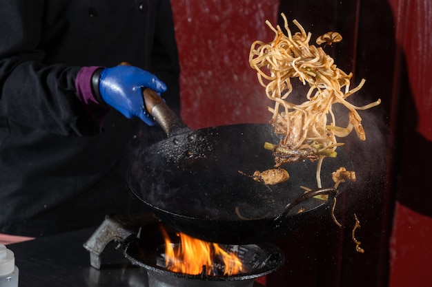 Foto fideos voladores para caja de wok con carne, salsa de soja frita en una sartén wok, comida callejera.